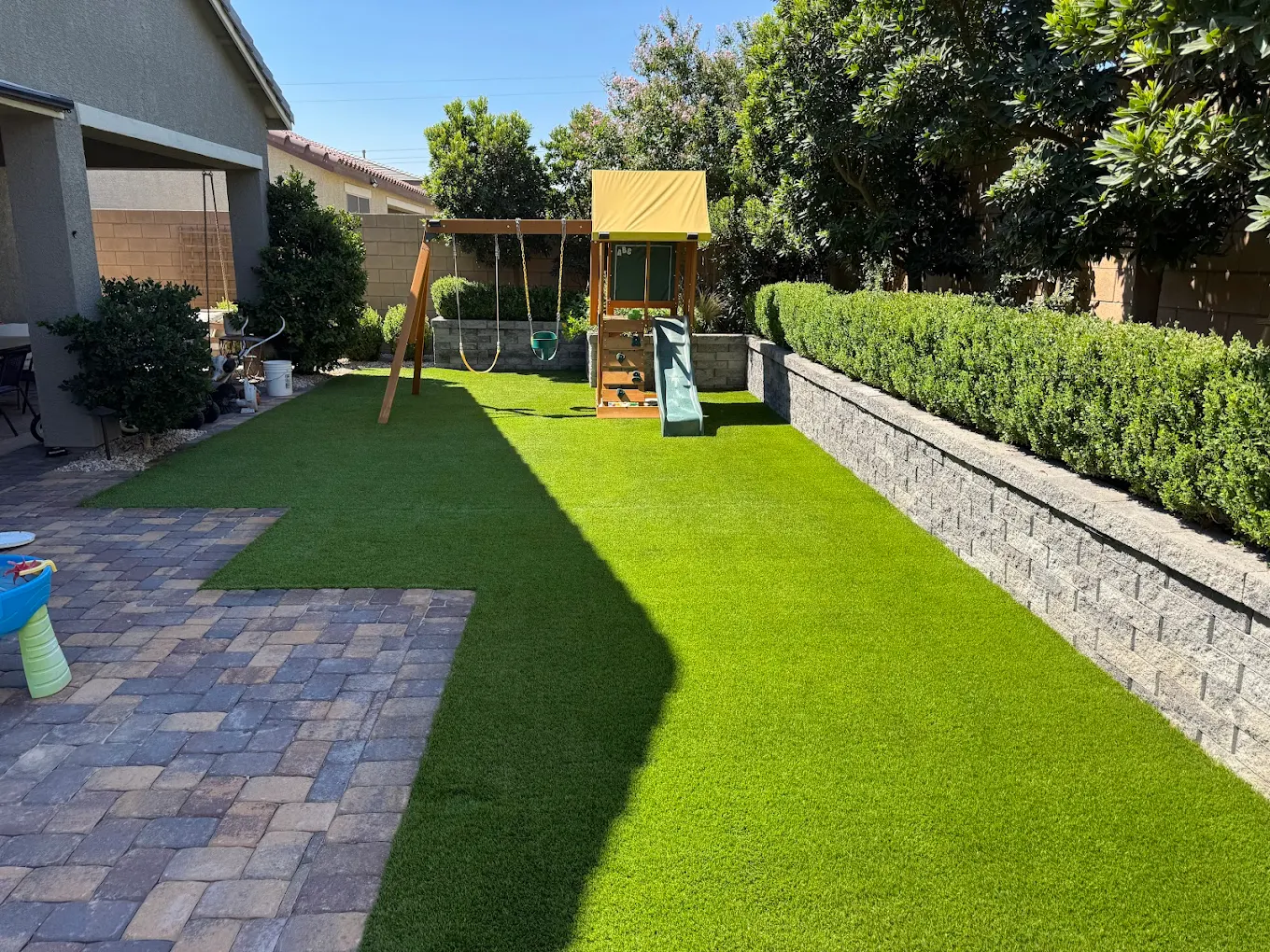 A pet-friendly Las Vegas backyard with artificial turf, pavers, and play area