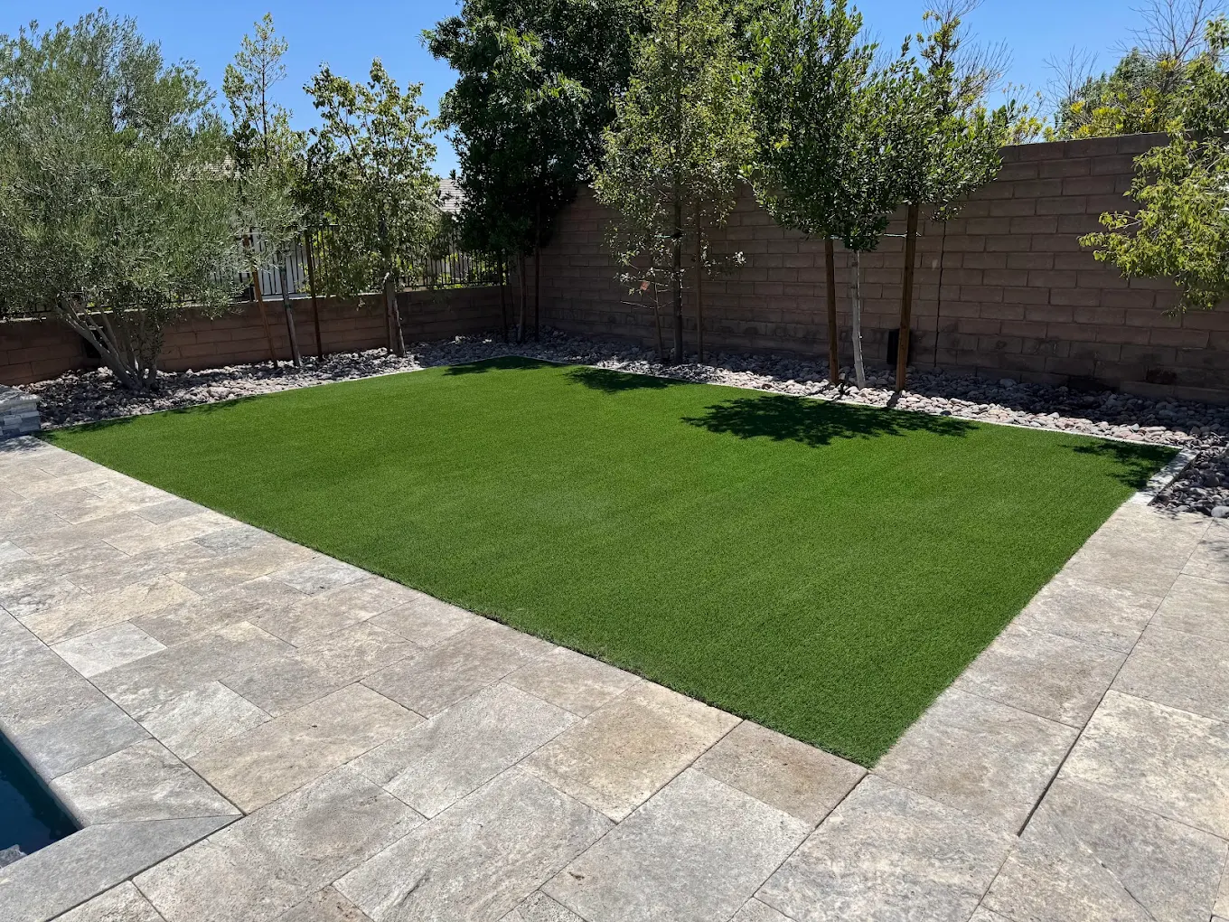 Clean artificial turf with stone pavers in a Las Vegas backyard